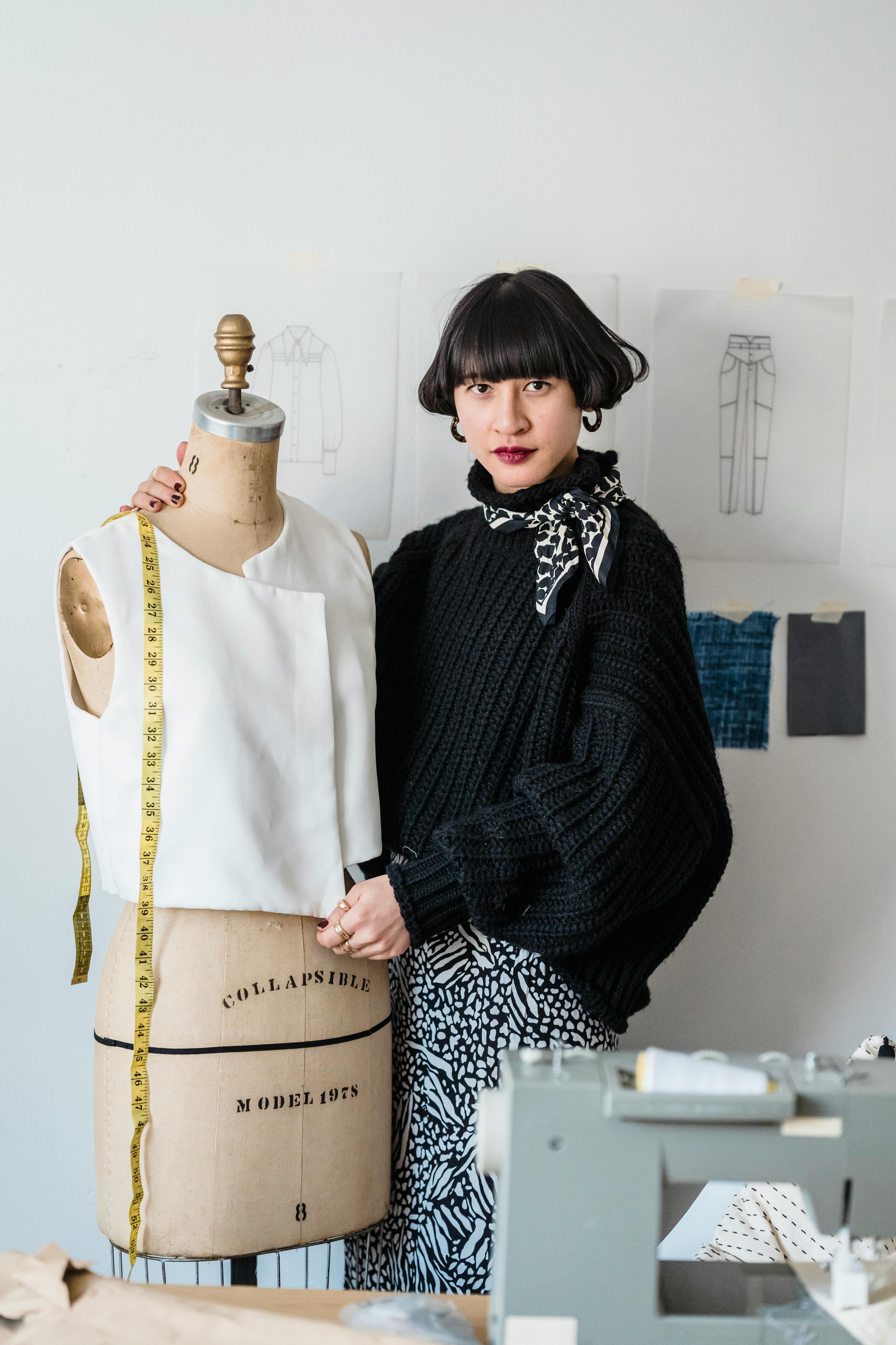 tailor with mannequin and measuring tape in workshop