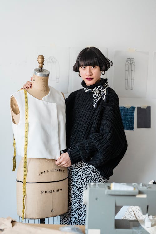 Tailor with mannequin and measuring tape in workshop