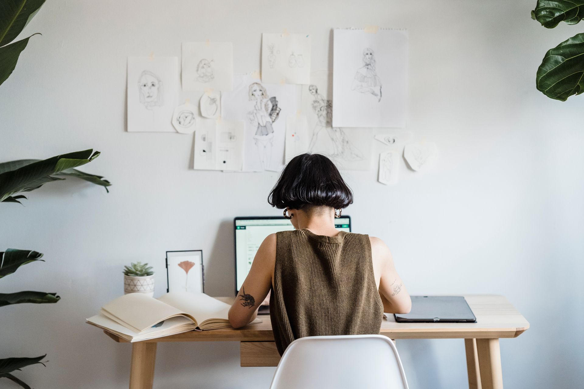 Focused female artist working on laptop in light room