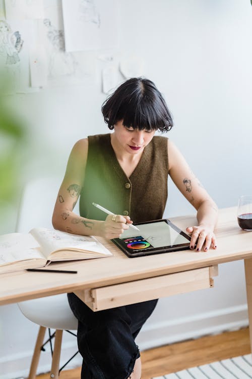 Free Asian woman drawing on graphics tablet while sitting in studio Stock Photo