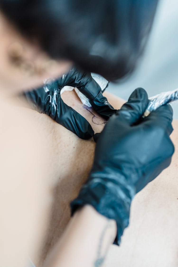 Close-up Of Person Drawing Tattoo On Body