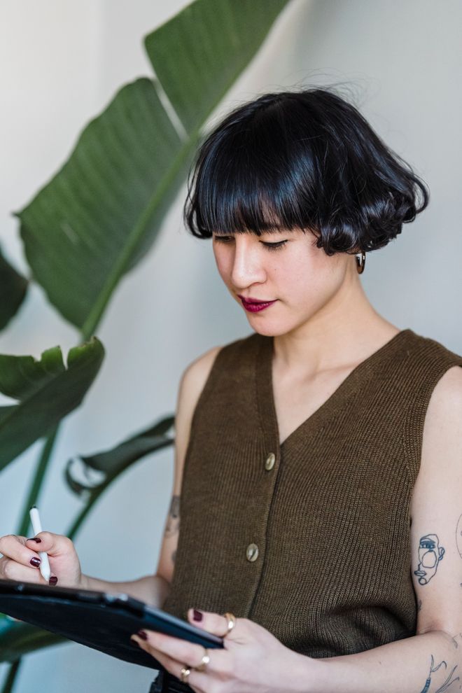 Person signing on a tablet with a stylus beside a plant — photo by Michael Burrows on Pexels