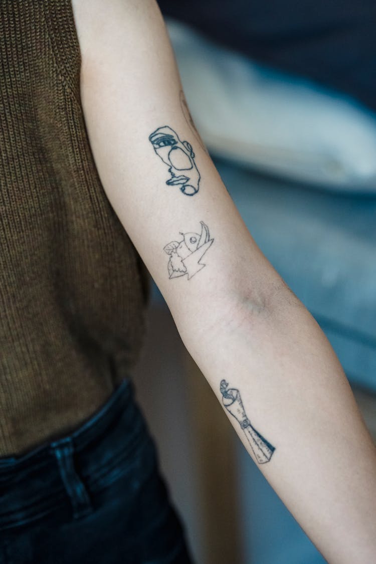 Crop Faceless Woman Showing Tattoos On Arm