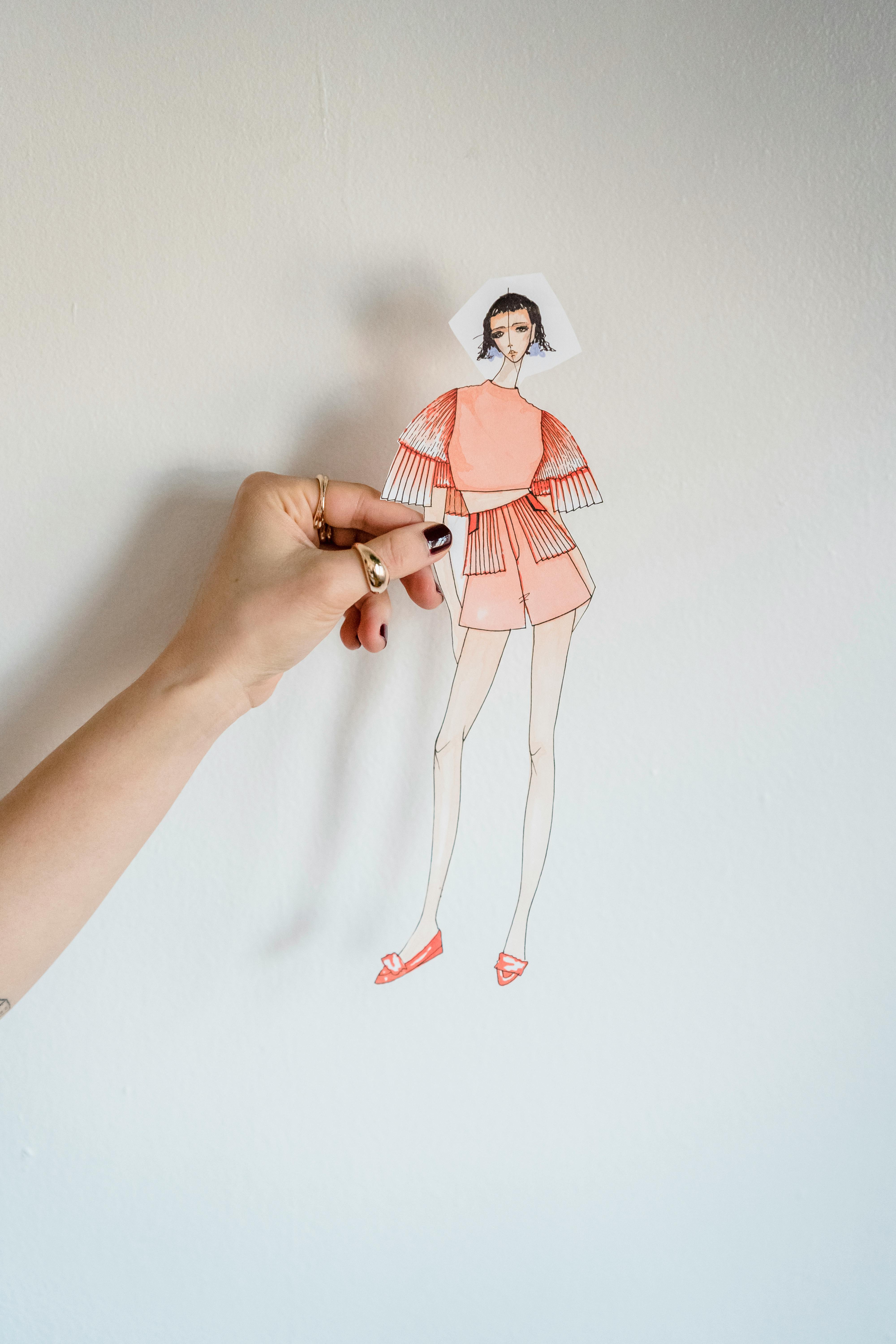 crop faceless female tailor showing fashion paper doll in studio