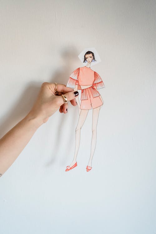 Crop faceless female tailor showing fashion paper doll in studio