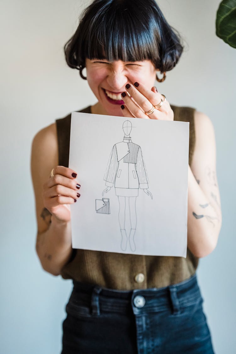 Cheerful Ethnic Woman Laughing While Showing Fashion Sketching In Studio