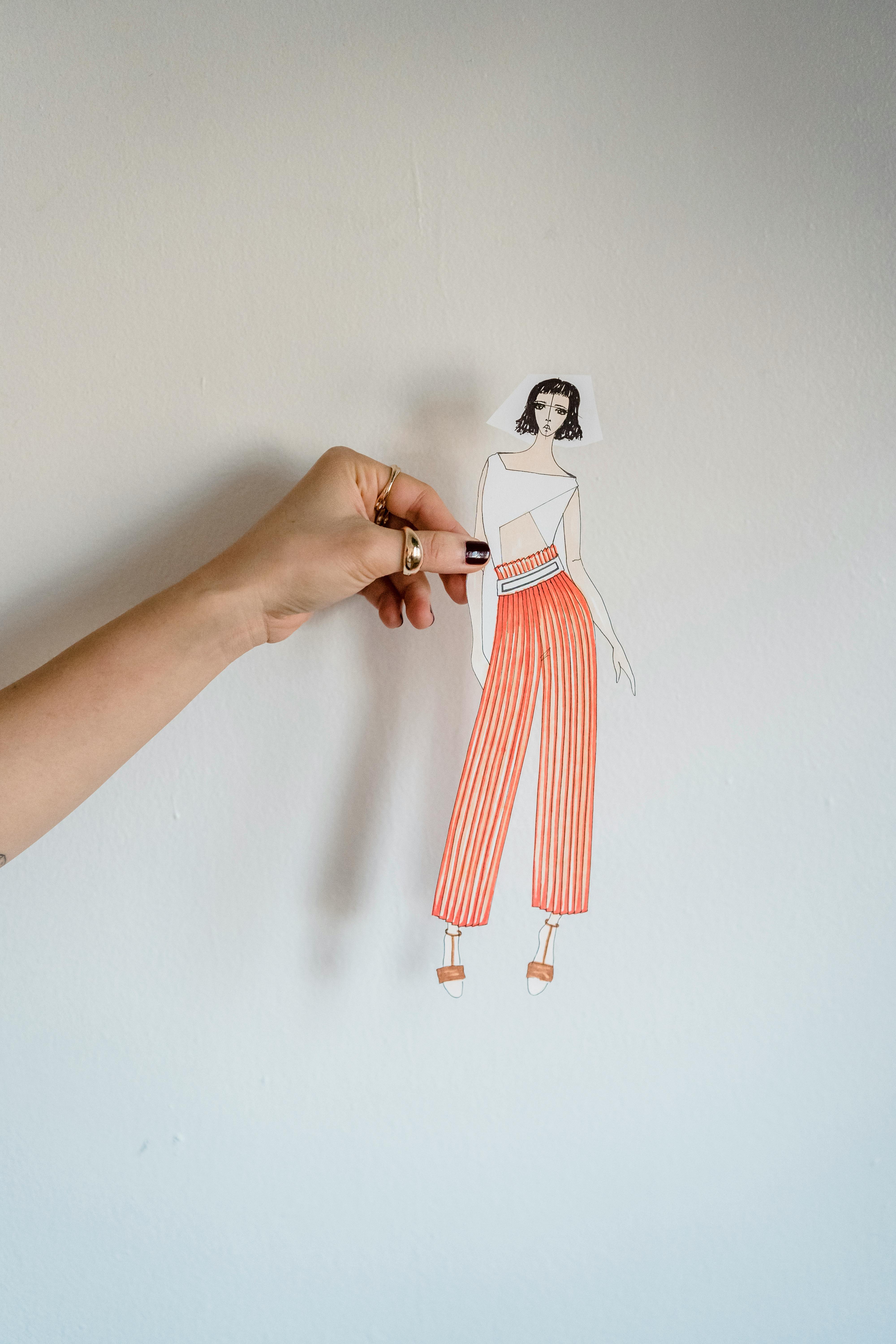 crop lady showing fashion illustration near wall in white studio