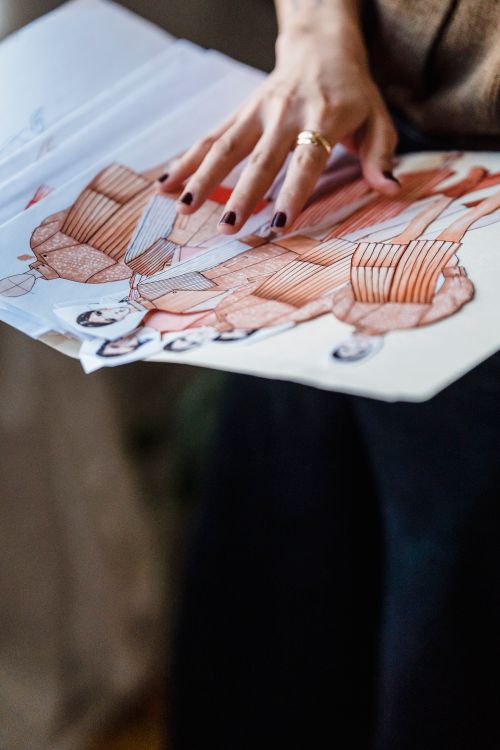 Free From above of crop anonymous designer holding folder with fashion sketches with various outfits and drafts in atelier Stock Photo