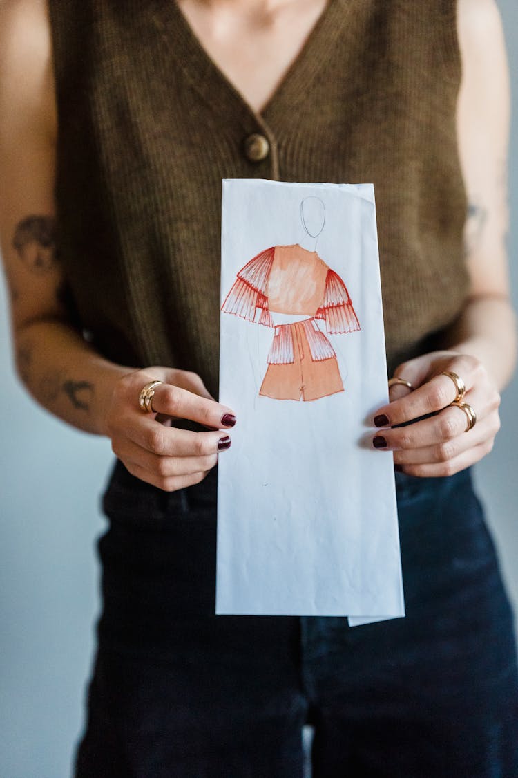 Crop Anonymous Woman Showing Paper Sheet With Fashion Illustration In Studio