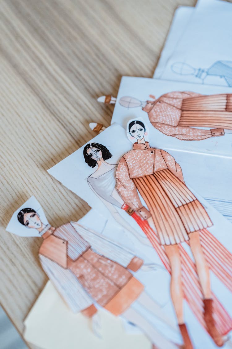 Collection Of Drawn Fashion Sketches On Wooden Table