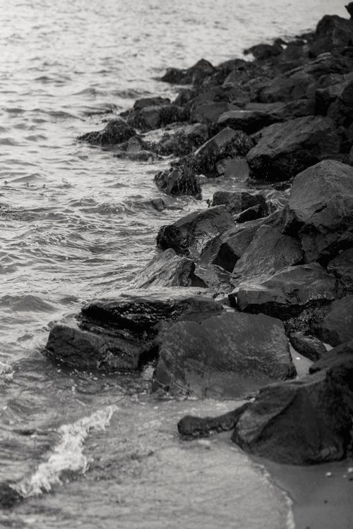 Free Black and white of wavy sea washing coast with rough stones in daytime Stock Photo
