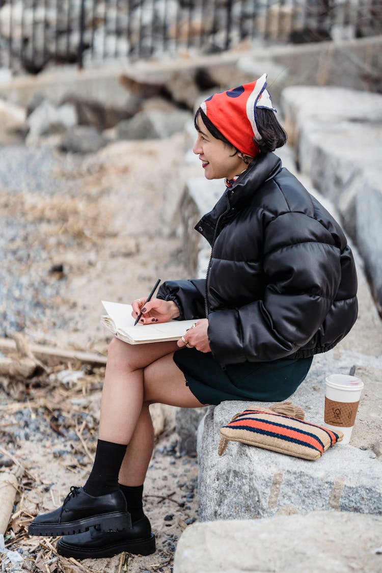 Smiling Ethnic Female Taking Notes In Notebook And Looking Away