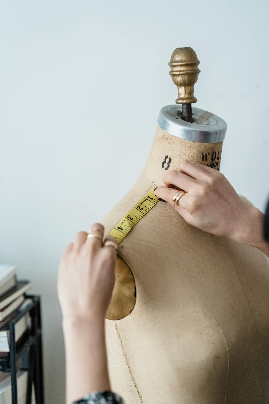 Seamstress measuring a mannequin to tag numbered pleats and hip points