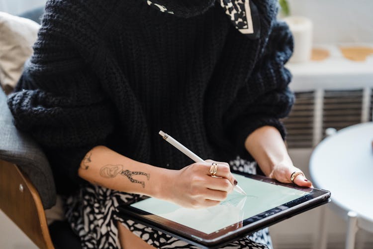 Female Illustrator Sitting And Drawing On Tablet Screen In Light Room