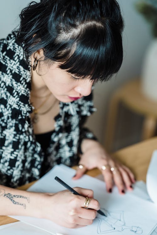 Focused young woman drawing sketch of clothes