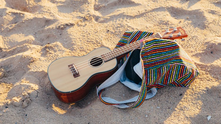 Beach Bag And Guitar On Beach Sand