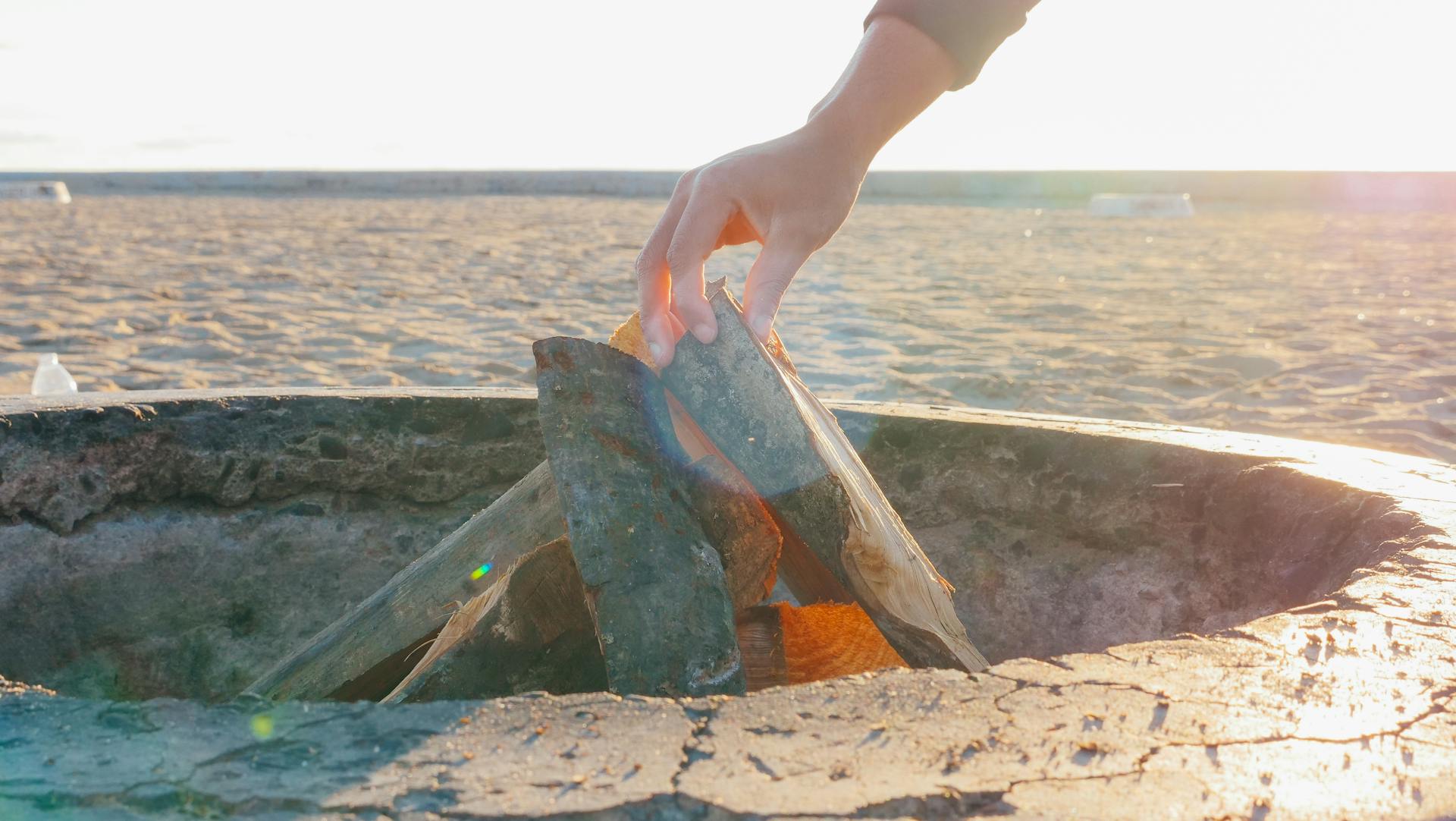 Person Holding Brown Wooden Log on Fire Pit