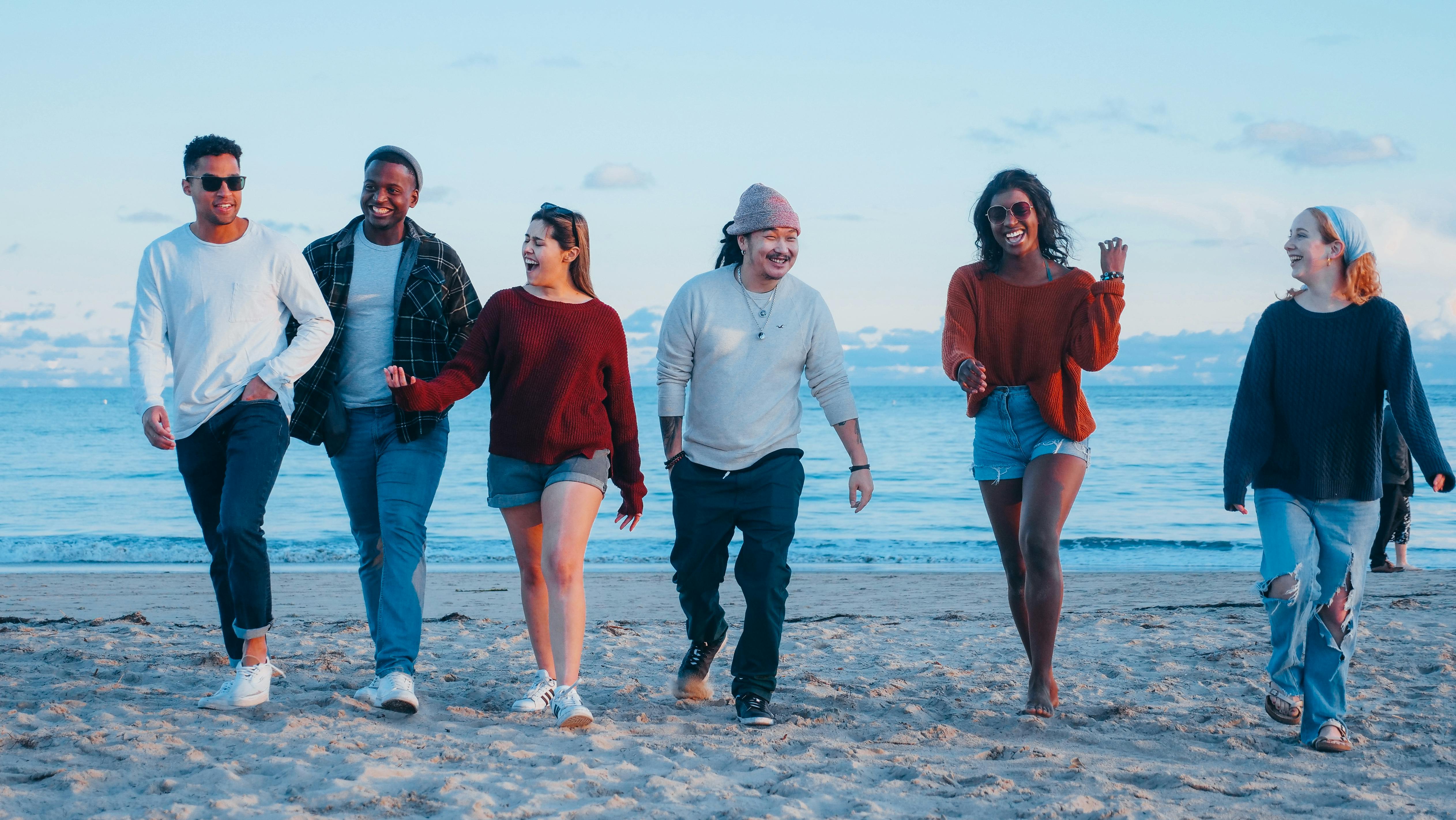 group of friends walking on beach shore