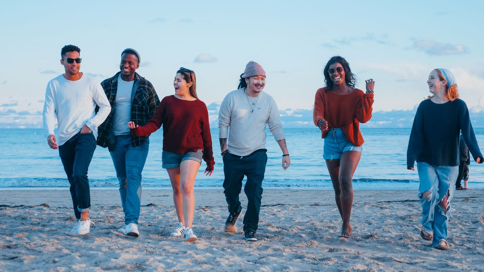 Friends walking together on a beach at golden hour.