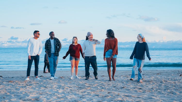 Group Of Friends Walking On Beach Shore