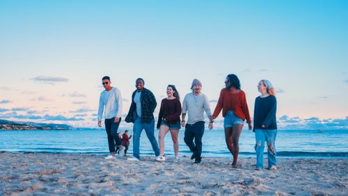 Free Friends walking on the beach at sunset, enjoying leisure and togetherness. Stock Photo