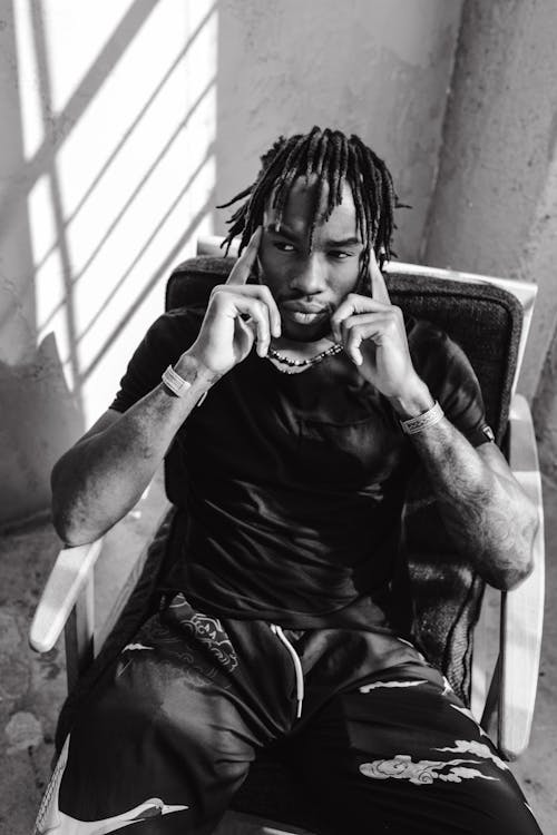 Monochrome Photo of a Man with Dreadlocks Sitting on a Chair