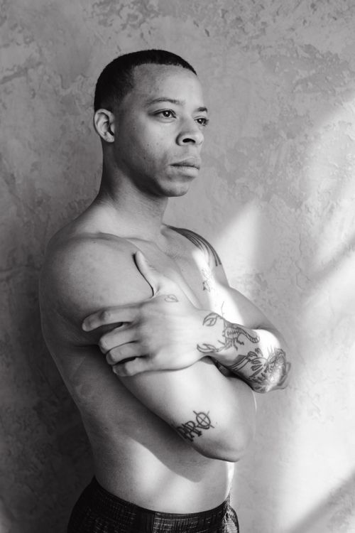 Free Black and white portrait of a shirtless tattooed man with arms crossed, conveying a serious mood. Stock Photo