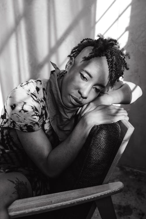 A Grayscale Photo of a Woman Sitting on the Chair