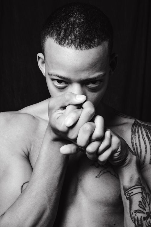 Free Black and white portrait of a tattooed man posing shirtless with intense gaze. Stock Photo