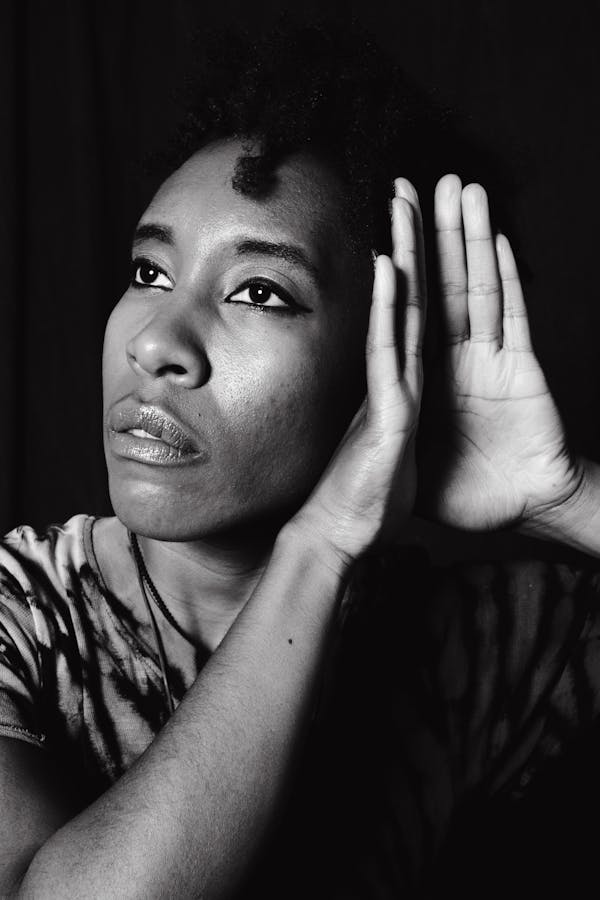 A Grayscale Photo of a Woman in Hearing Position of Her Hands