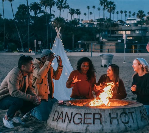 Free Group of Friends Sitting in Front of Fire Pit Stock Photo
