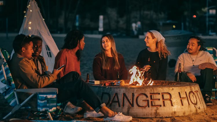 Group Of Friends Sitting In Front Of Fire Pit