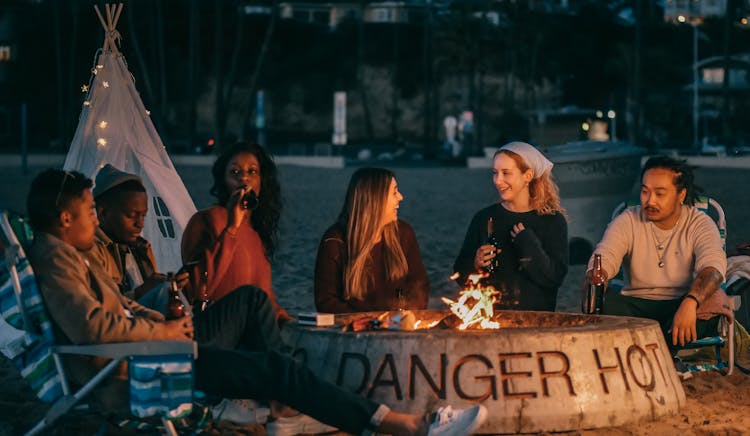 Group Of Friends Sitting In Front Of Fire Pit