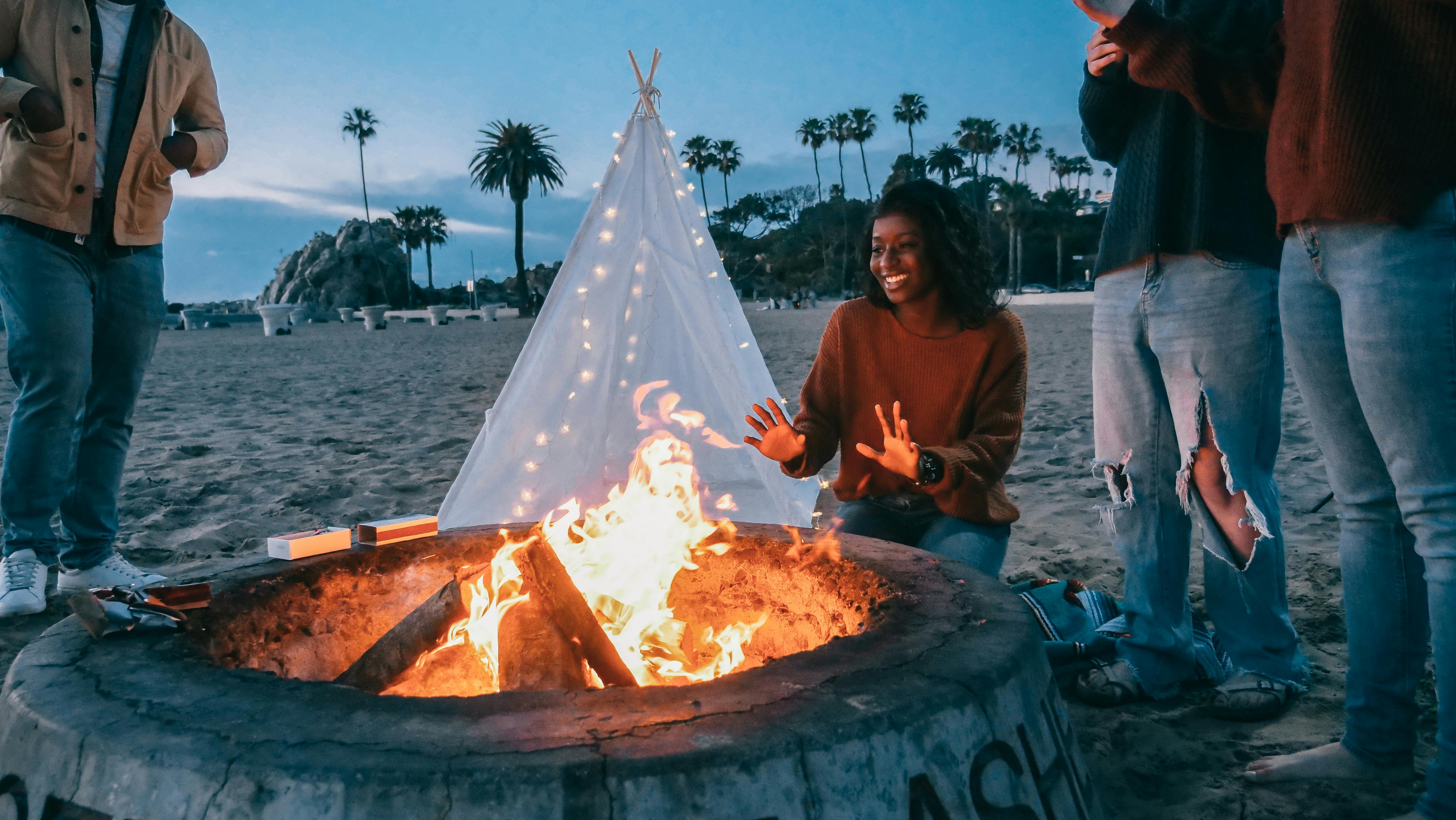 woman warming her hands in front of the fire pit