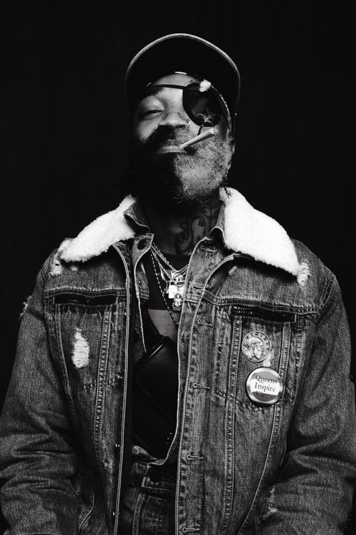Free Black and white portrait of a man in denim jacket smoking with an eyepatch on black background. Stock Photo
