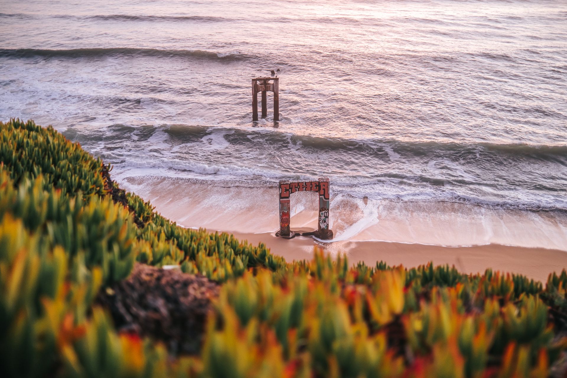 Aerial view of Davenport Pier ruins with coastal waves and vibrant sunset colors.