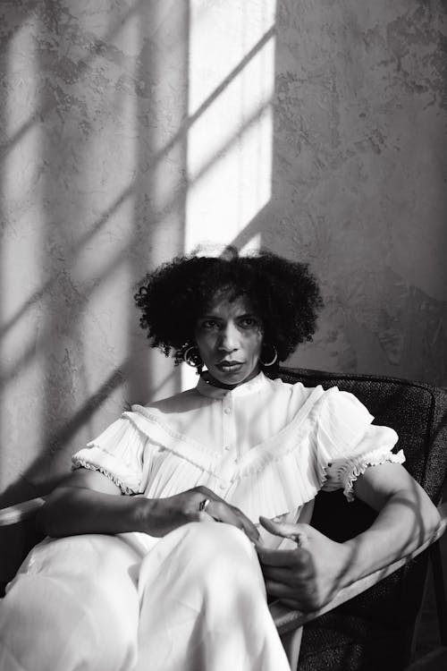 A Grayscale Photo of a Woman Sitting on a Chair