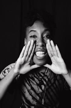 A vibrant black and white portrait of a woman expressing joy and enthusiasm in a studio setting.