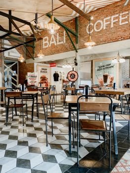 Rustic cafe interior with wooden tables and chairs, exposed brick walls, and decorative lighting.