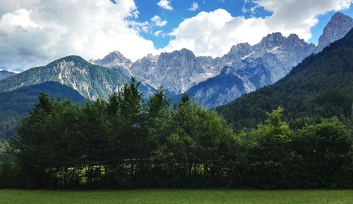 Free Breathtaking view of mountain peaks with lush green trees in foreground under a cloudy sky. Stock Photo