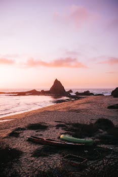 Tranquil sunset view of Martins Beach, CA with kayaks on the shore.