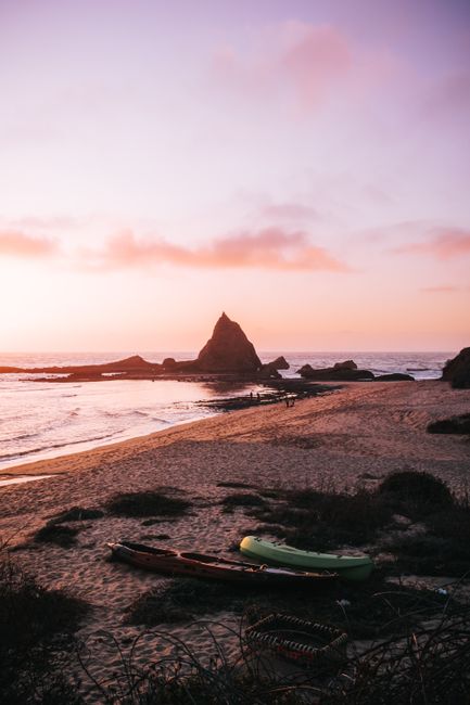 Tranquil sunset view of Martins Beach, CA with kayaks on the shore.