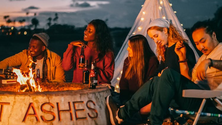 Group Of Friends Sitting In Front Of Fire Pit