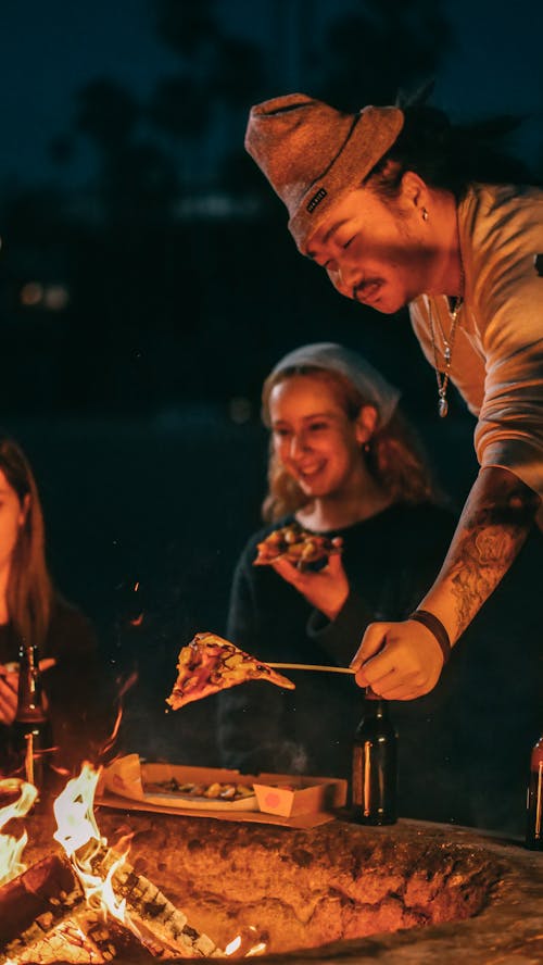 Free Man Heating His Pizza on a Bonfire Stock Photo