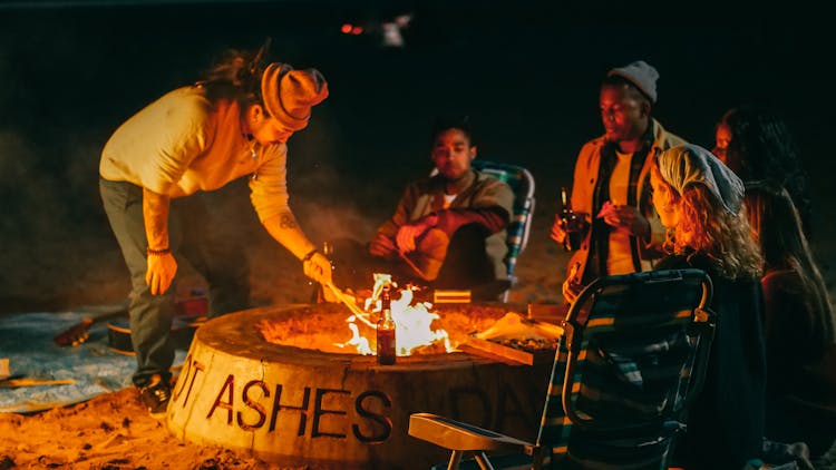 Group Of Friends Sitting In Front Of Fire Pit