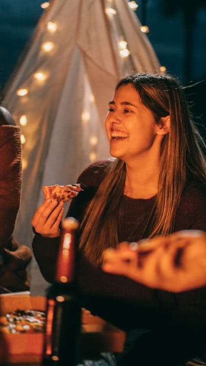 Free Group of friends enjoying pizza and drinks at a cozy nighttime hangout. Stock Photo