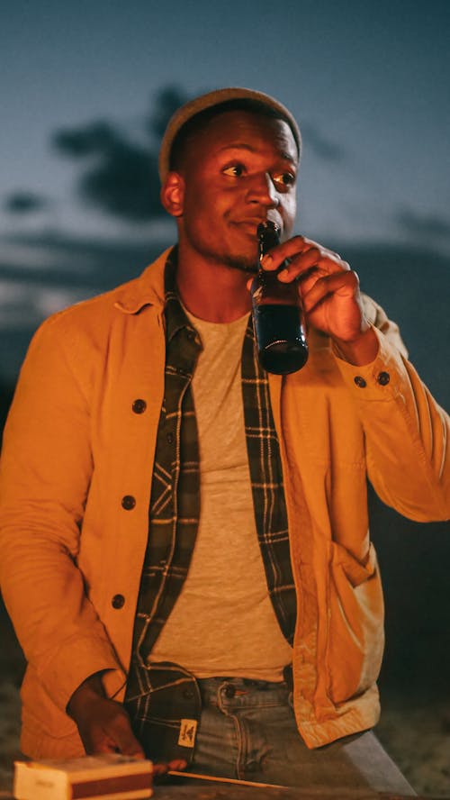 Free Man in Brown Jacket Drinking a Beer Stock Photo