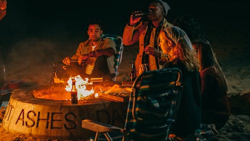 Free Group of Friends Eating in Front of Fire Pit Stock Photo