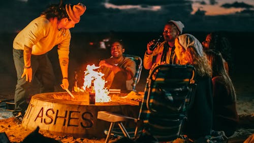 Free Group of Friends Sitting in Front of Fire Pit Stock Photo