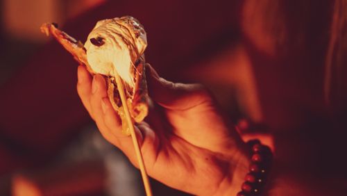 Free Close-up view of a hand holding a gooey s'more with melted marshmallow over a campfire. Stock Photo